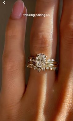 a woman's hand with a ring on it and an engagement ring on her finger