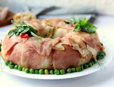 a plate with meat covered in vegetables and garnishes on the top, sitting on a table next to utensils