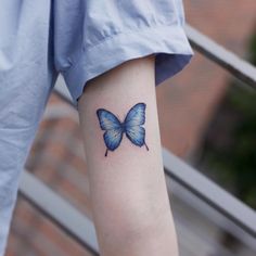 a small blue butterfly tattoo on the arm