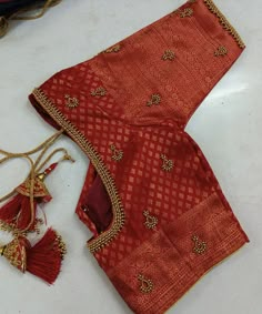 an orange and red sari with tassels on the side, sitting on a white surface