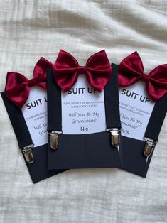 three pieces of paper with red bow ties on them sitting on top of a white sheet