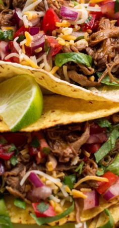 two tacos with shredded beef, onions, peppers and cilantro on top