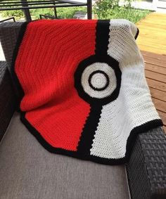 a crocheted blanket is sitting on a couch with a black, white and red afghan