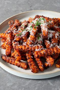 a white plate topped with fried chicken wings covered in parmesan cheese