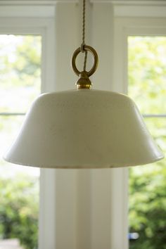 a white lamp hanging from a ceiling in a room with two windows and a window sill