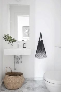 a white bathroom with a basket on the floor