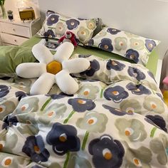 a bed with two pillows and a stuffed flower on top of the pillowcases