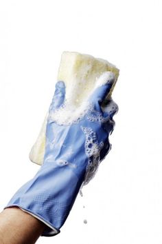 a hand with blue gloves holding a sponge on it's palm and water droplets coming out of the glove