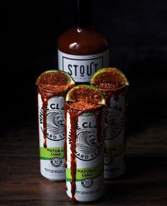 three bottles of hot sauce sitting next to each other on top of a wooden table