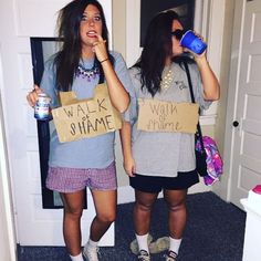 two girls are standing in the hallway drinking water and talking on their cell phones while holding signs