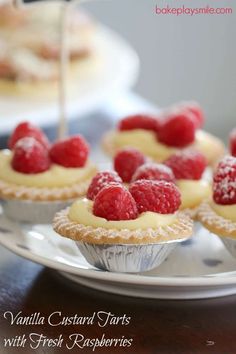 raspberry tarts with fresh raspberries are on a plate and ready to be eaten