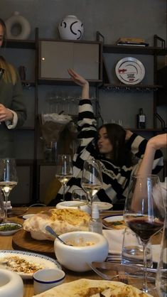 two women sitting at a table with plates of food and wine glasses in front of them