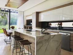 a kitchen with marble counter tops and bar stools next to an open floor plan