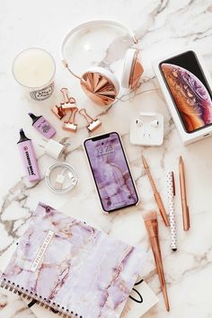 the contents of a personal care kit laid out on a marble counter top, including an iphone