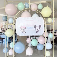 there is a sign that says mickey mouse and balloons hanging from the ceiling in front of it