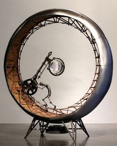 a metal sculpture with a clock inside of it's center wheel on top of a stand