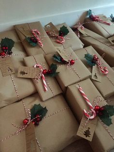 many wrapped presents with candy canes and holly leaves on them, all tied up in twine