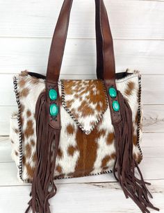 17" wide x 12" tall Hide outer, fabric lined tote with fringe and synthetic turquoise stone.  Get the look without the price!  Open at top with flap with magnetic clasp zipper and 2 open pockets inside Lightweight bag with light weight straps unlike the solid leather that can we heavier.  Not customizable - handmade by Klassy Cowgirl Hide patterns WILL vary. Select from drop down menu** Custom Purses, Cowhide Purse, Boho Styl, Looks Country, Cowhide Bag, Used Louis Vuitton, Brown Cowhide, Upcycled Leather, Kandy