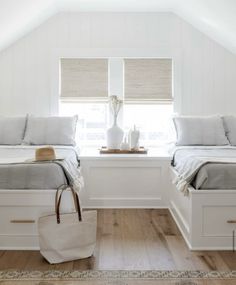 two beds in a room with white walls and wooden floors, one has a tote bag on the floor