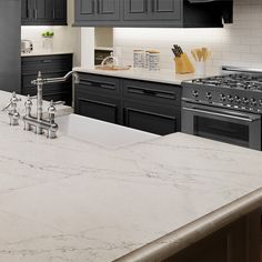 a kitchen with marble counter tops and black cabinets, along with stainless steel oven hoods