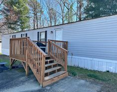 a mobile home with stairs leading up to the front door and side porch area next to it