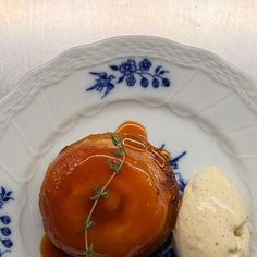 a plate topped with an orange covered dessert and ice cream on top of blue and white plates