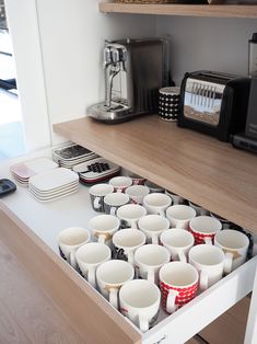 a drawer full of coffee cups on a kitchen counter