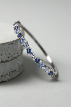 a close up of a bracelet on top of a piece of concrete with blue and white stones