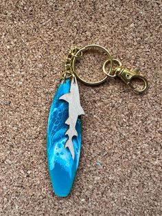 a blue keychain with an airplane on it sitting on a brown carpeted floor