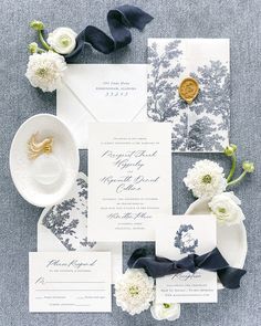 the wedding stationery is laid out with white flowers and blue ribbon, which are tied together