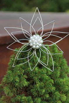 a small christmas tree with pearls on it's top and leaves in the middle