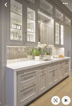 a kitchen with gray cabinets and white counter tops is shown in this image, there are flowers on the counter