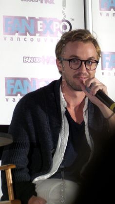 a man with glasses sitting in front of a microphone