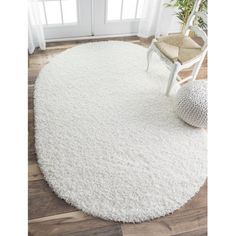 a white rug in the corner of a room with a chair and potted plant