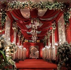 a red and white wedding ceremony setup with chandelier, flowers, and aisle