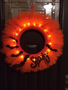 an orange wreath decorated with bats and lights