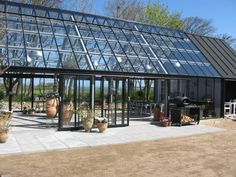 a glass house with potted plants in the yard