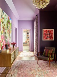 a living room with purple walls and an area rug on the floor that has a painting hanging above it