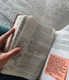 a person holding an open book with sticky notes on it and pointing to the page