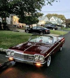 an old car is parked on the side of the road in front of some houses