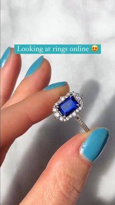 a woman's hand with blue nail polish holding an engagement ring on her finger