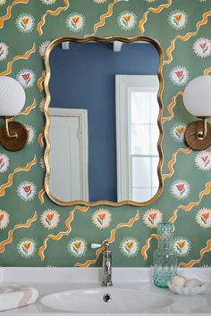 a bathroom sink with a mirror above it and a wallpapered wall behind it