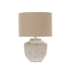 a white table lamp with a beige shade on the base and a light brown drum