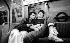 two people sitting on a subway car with their faces close to each other as they look up at the sky