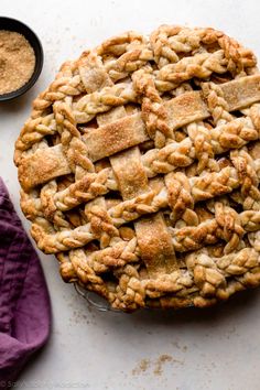 a pie sitting on top of a white table next to a purple napkin and bowl