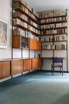 a room with many bookshelves and a chair in the corner next to it