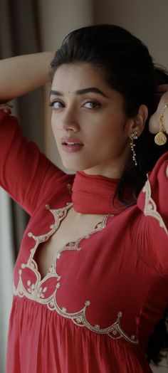 a woman in a red dress is posing for the camera with her hand on her head