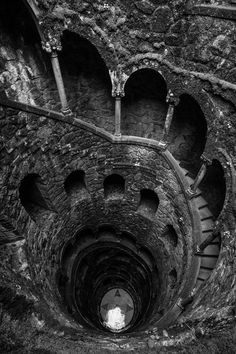 a spiral staircase with moss growing on the walls and steps leading down to the top