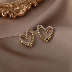 You'll fall" Love with these sparkling studs boasting intertwined cubic zirconia and beaded hearts for double the romance. 0.71" W x 0.83" H 18k gold-plated copper / cubic zirconia Gold Heart Earrings With Rhinestones For Valentine's Day, Gold Heart-shaped Earrings With Rhinestones, Gold Rhinestone Heart Earrings, Elegant Rhinestone Heart Earrings As Gift, Valentine's Day Gold Rhinestone Jewelry, Gold Diamond Heart Earrings For Wedding, Valentine's Day Gold Jewelry With Sparkling Stones, Gold Heart-shaped Earrings With Diamond Accents, Gold Heart Shaped Earrings With Diamond Accents