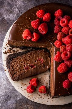 a chocolate cake with raspberries on top and one slice missing from the cake